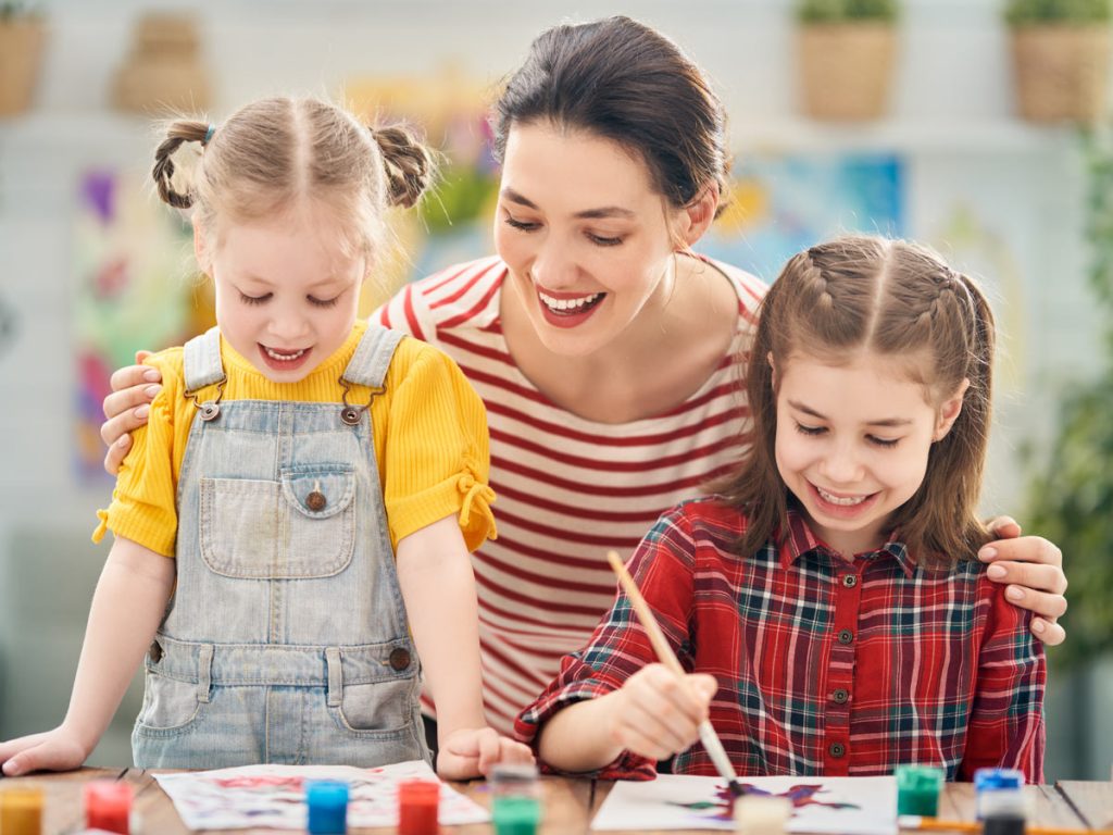 Photo of a woman painting with young children